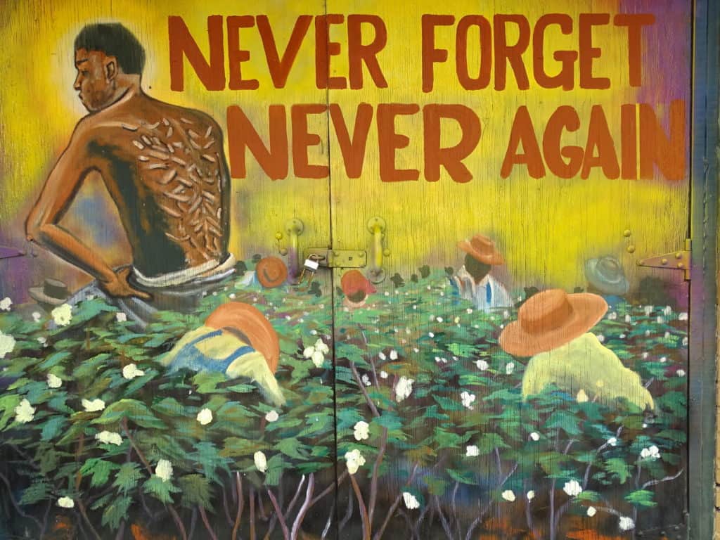 Mural depicting black slave with lacerated back in a cotton field and the words "Never Forget, Never Again." Selma to Montgomery National Historic Trail.