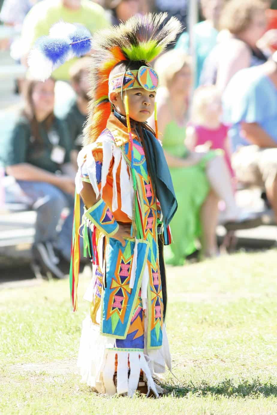 A Native American boy stands proudly in the ancestral garb of his people.