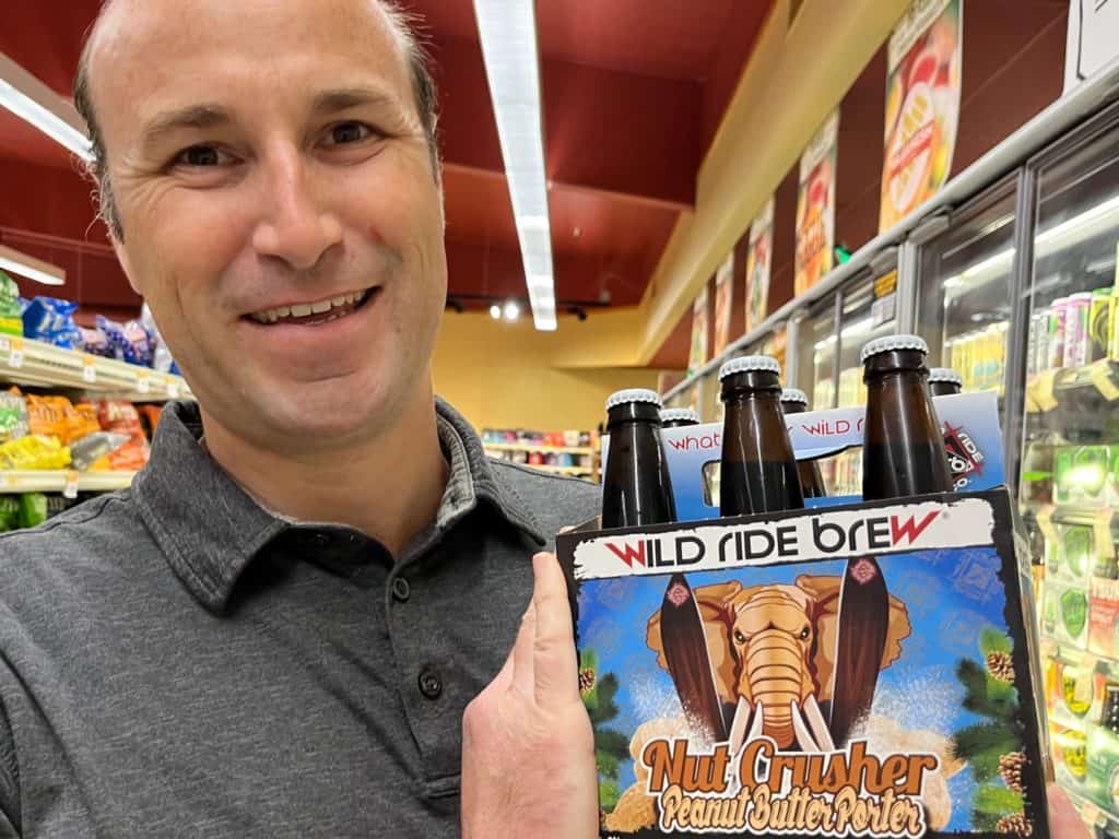 Man holding craft beer at a local grocery store. One of the best gifts from Oregon are the local craft beers.