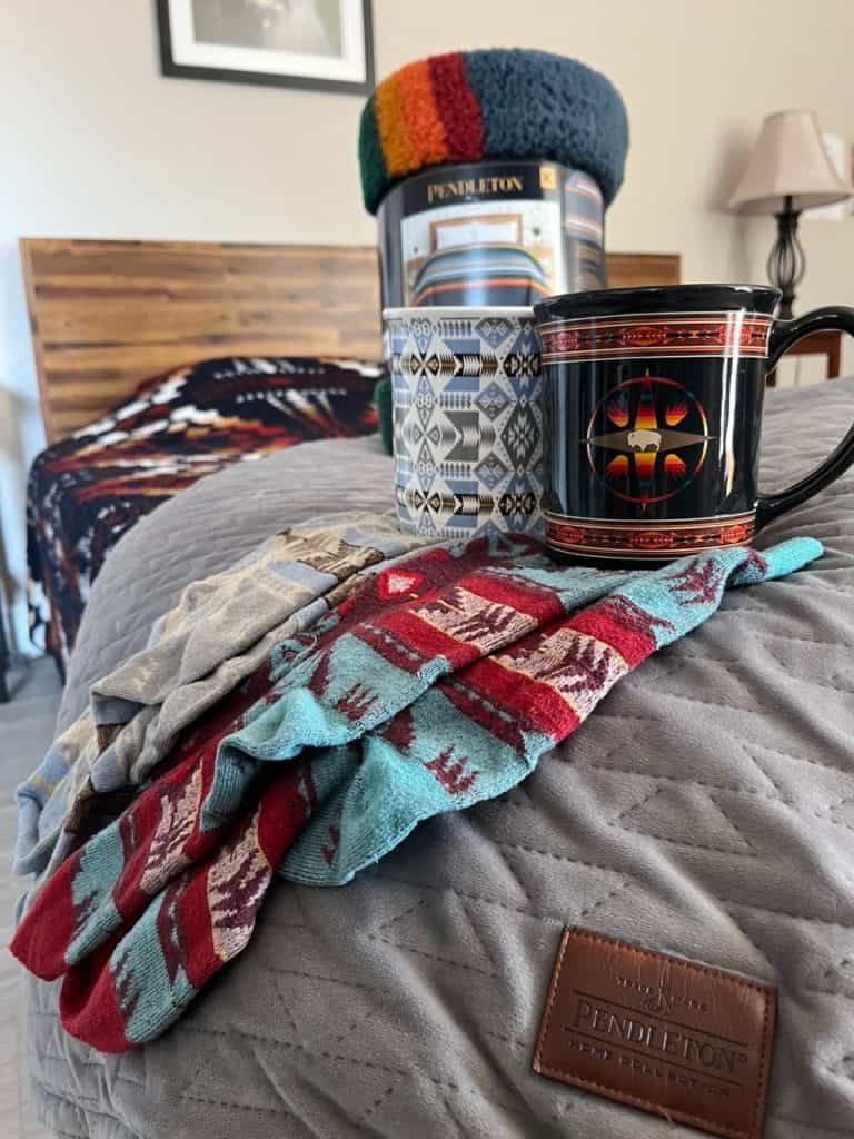 The picture displays some great Pendleton products including three Pendleton blankets, two mugs, and two pairs of socks. Pendleton makes some of the best gifts from Oregon.