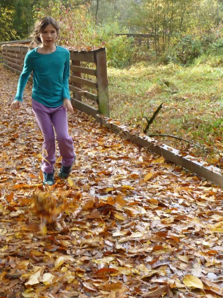 Girl walking through pile of leaves. Fall activities for teens
