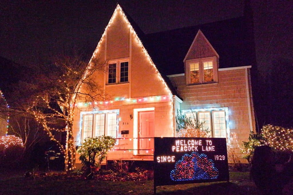 A decorated home sports a lighted holiday sign that says "Welcome to Peacock Lane, since 1929." Best places to see Christmas lights in Portland, Oregon