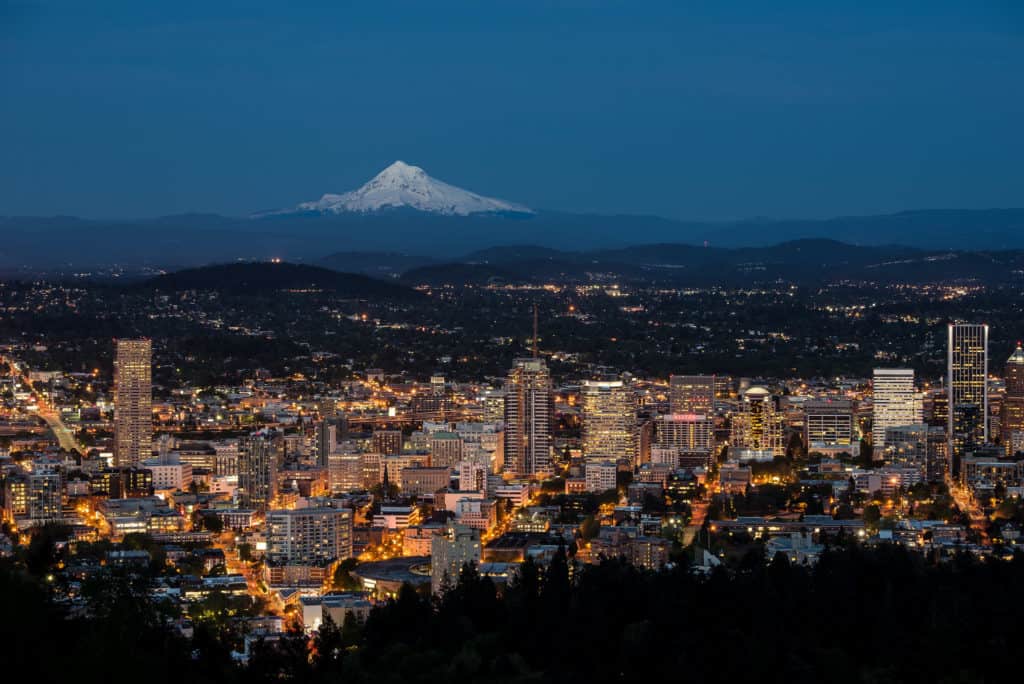 Downtown lights illuminate Portland under the snowy peak of Mount Hood. This view makes the Pittock Mansion one of the best places to see Christmas lights in Portland.