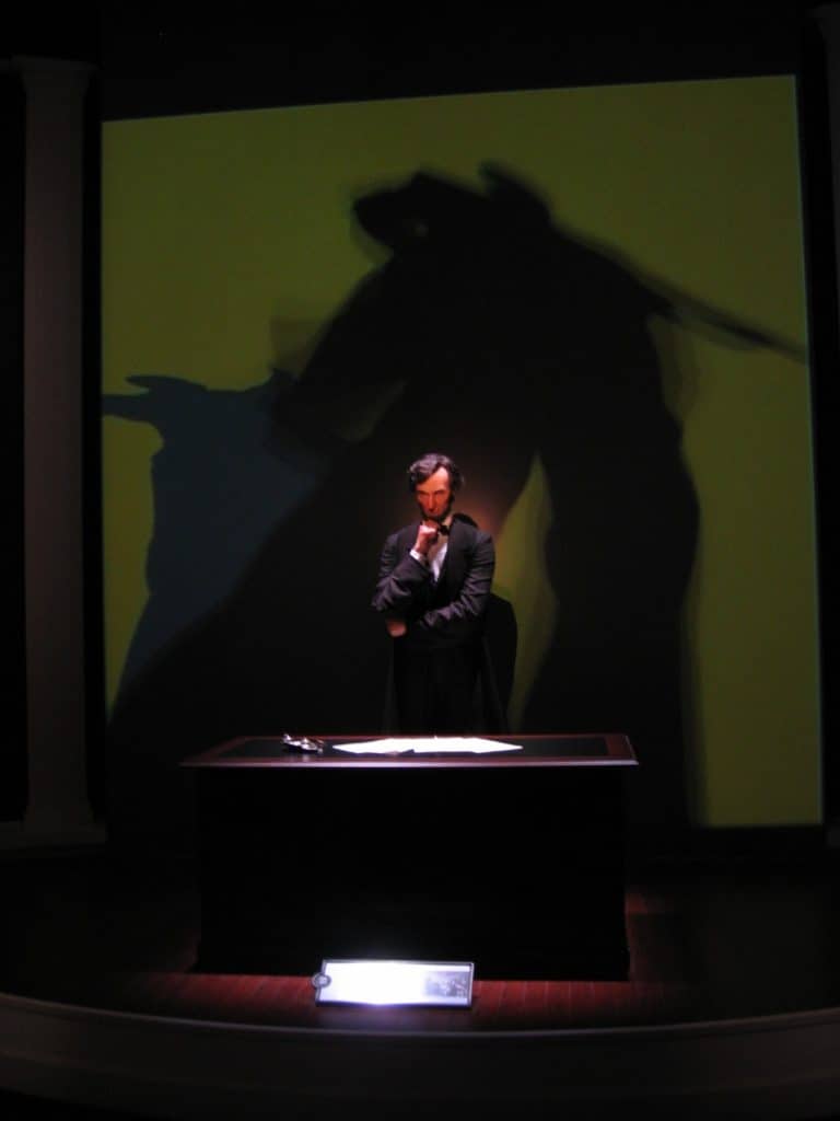 Lincoln stand behind his desk, pondering an important matter, in a life-size reproduction at the Abraham Lincoln Library and Museum.