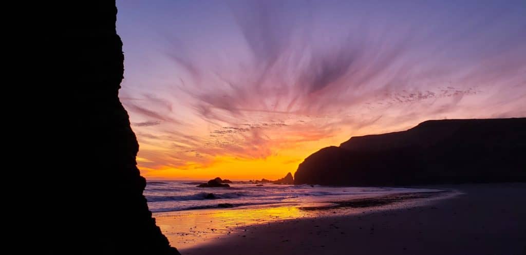 A beautiful sunset creates a sillouette out a coastal headland on the Oregon Coast. The Oregon Coast is the one of the 15 best Portland Oregon day trips for families.