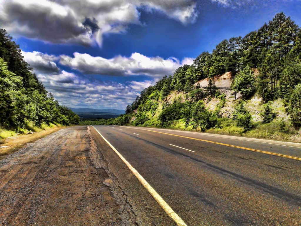 A road cuts through forested hills on a beautiful sunny day in Oklahoma. Image by Johnathan C. Wheeler / Wikimedia Commons. list of national parks and monuments by state