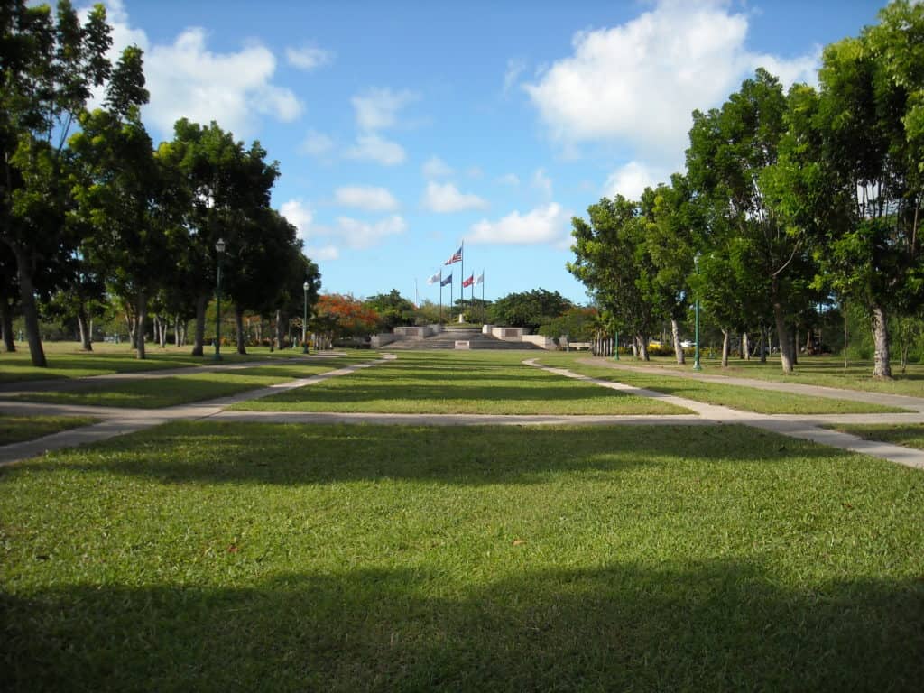 Tropical trees frame the United States flag and the flags of the Armed Forces at American Memorial Park in the Northern Marianas Islands. All of the national parks in US territories are listed in Dinkum Tribe's list of national parks and monuments by state. Image from NPS.