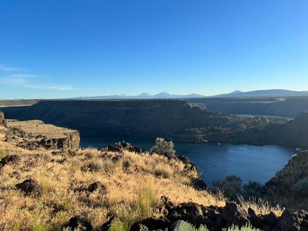 Cascade peaks line the horizon behind the rocky crags and blue waters of Lake Billy Chinook. Cove Palisades State Park is one of the 15 best Portland Oregon day trips for families. 