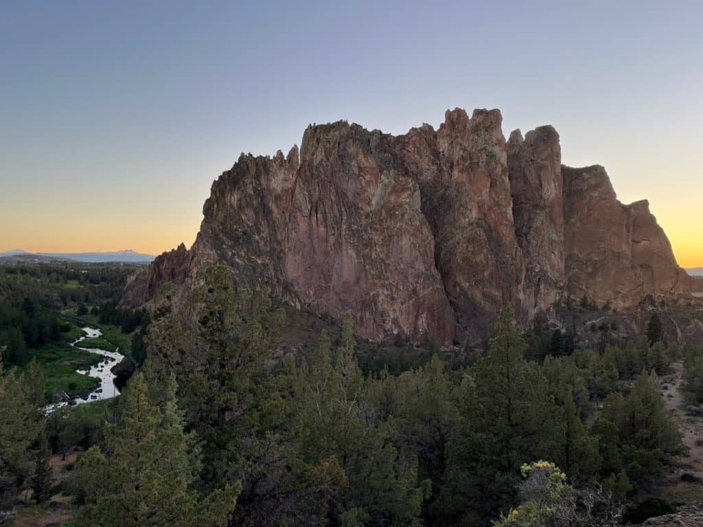 Sunset gilds the horizon behind a gargantuan rock formation at Smith Rock State Park. Smith Rock State Park is one of the 15 best Portland Oregon day trips for families.
