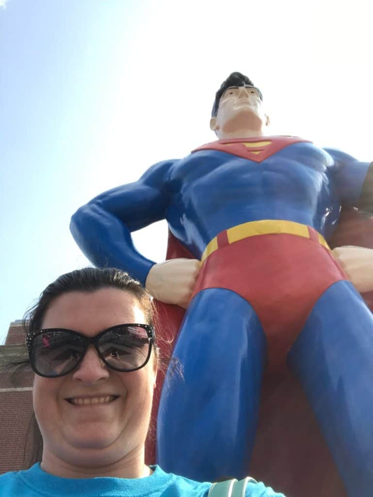 My wife smiles in a big selfie beside Metropolis' Superman statue.