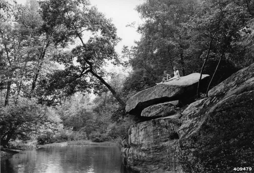 Two young women sit on an enormous rock at Bell Smith Springs Scenic Area. 