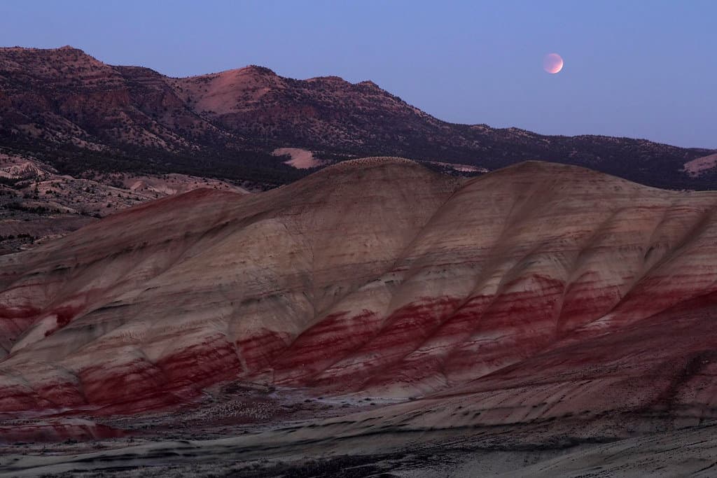 The moon rises over the Painted Hills at John Day Fossil Beds National Monument. John Day Fossil Beds National Monument is one of the best national parks in Oregon and Washington. 