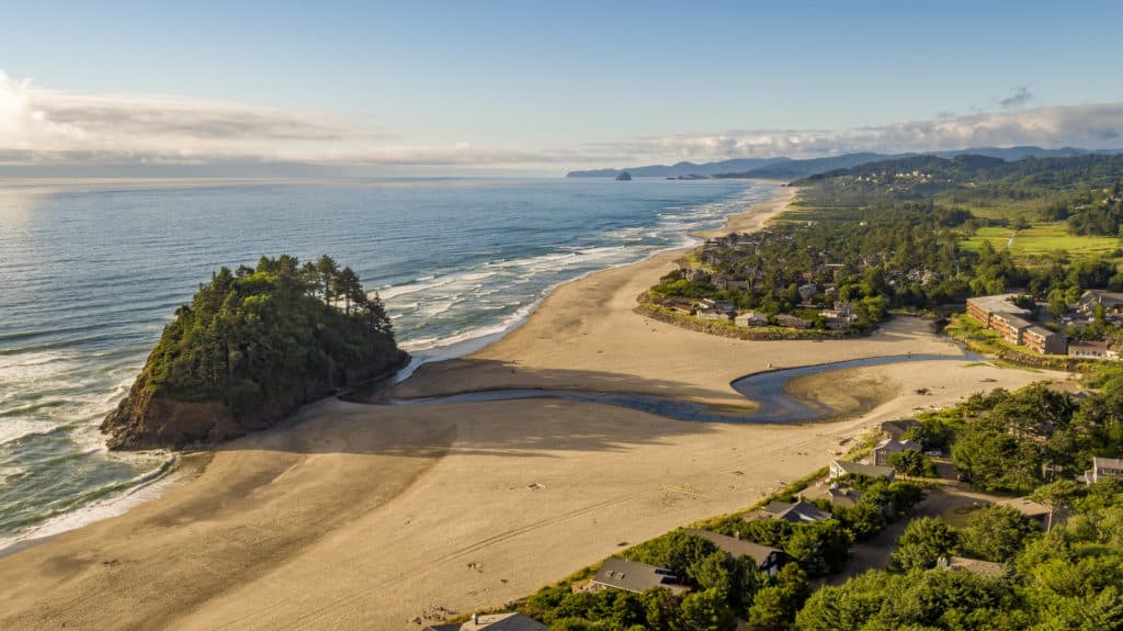 The long shadow of a forested sea stack reaches across beautiful Neskowin Beach. Neskowin Beach is one of the 21 best beaches in Northern Oregon.