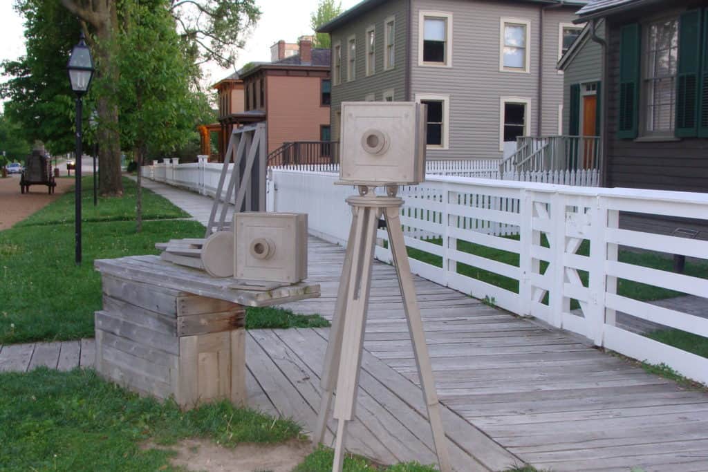 Replicas of 19th century photography equipment stand beside a boardwalk at Lincoln Home National Historic Site.