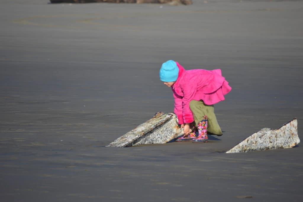 My little daughter tries her best to lift the steel shipwreck out of the sandy beach. 
