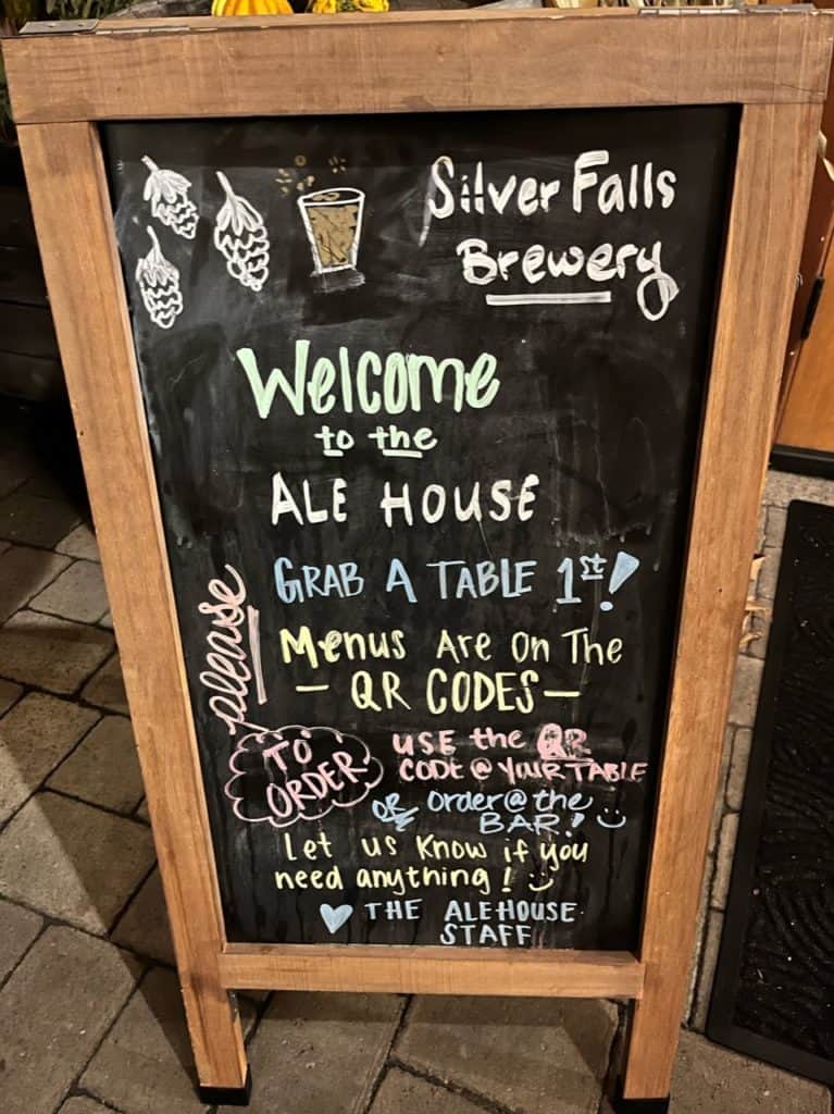 A chalkboard sign welcomes you to the ale house and gives directions on how to get settled in and started on the ordering process. 