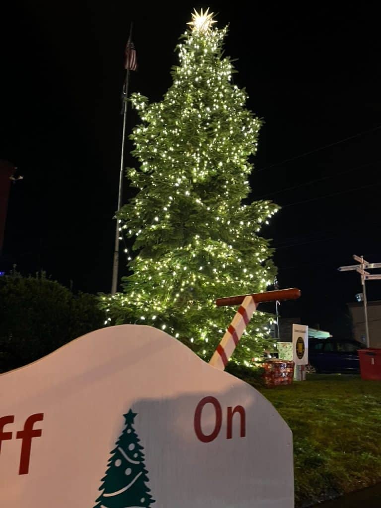 An enormous holiday switch stands in front of Mt. Angel's town Christmas tree. Mt. Angel is one of the 11 best places to see Christmas lights in Salem Oregon.