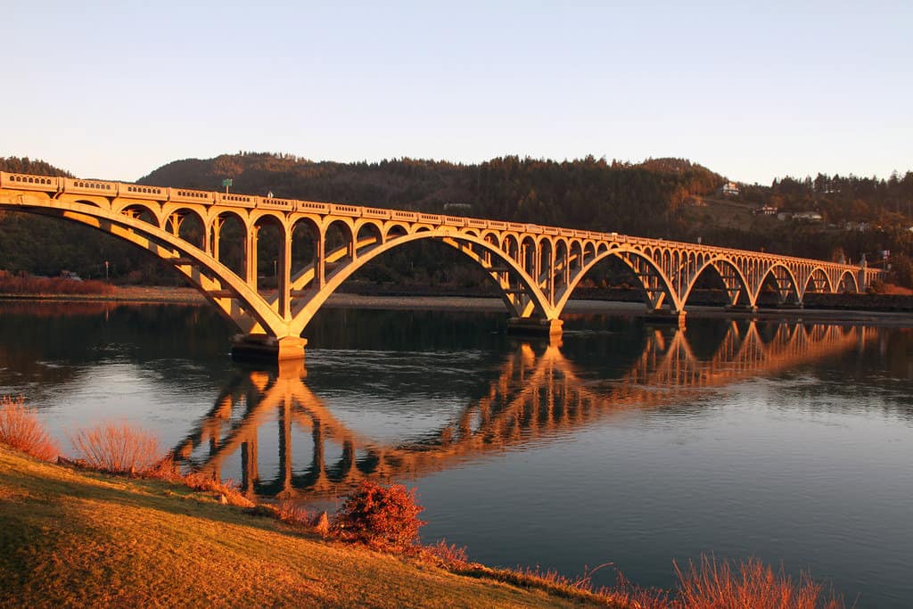 Evening sunlight gilds a historic bridge in Gold Beach, Oregon.