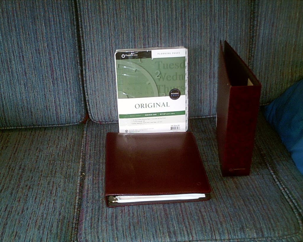 A thick, plastic wrapped pack of planner pages stands beside a Franklin Planner notebook and a Franklin Planner archival folder.