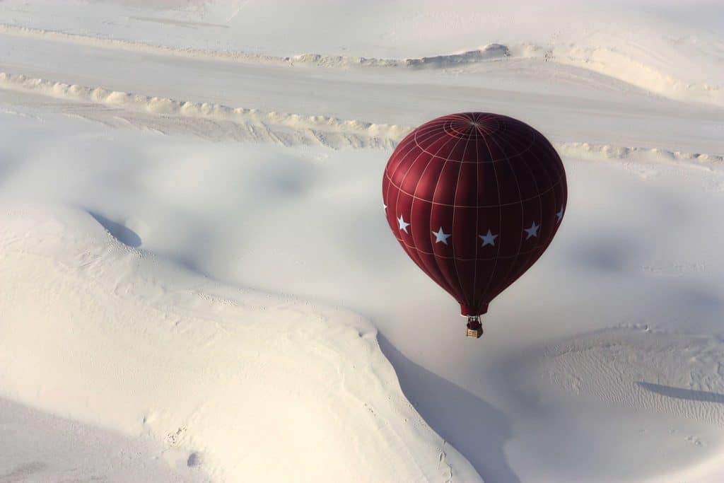 An air balloon floats above the dunes at White Sands National Park. White Sands National Park is one of the best national parks to visit in November and December.