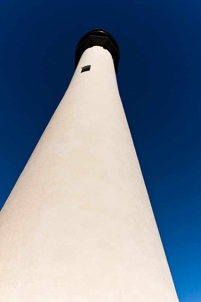 A white lighthouse reaches for the sky at Biscayne National Park. Biscayne National Park is one of the best national parks to visit in November and December.
