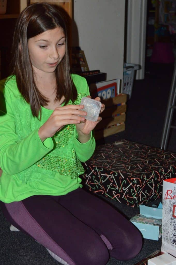 Girl unwrapping a gift. Family Christmas bucket list.