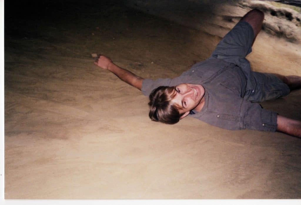 Me as a young man lays on my back in a cave smiling. 