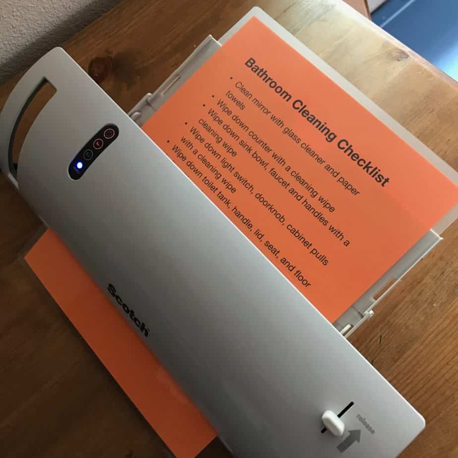 Laminator in process of laminating bathroom cleaning list. Best gifts for homeschool moms.