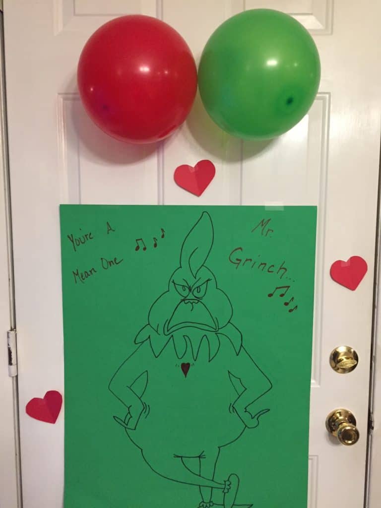 Hand-drawn poster of the Grinch on green paper with red hearts.