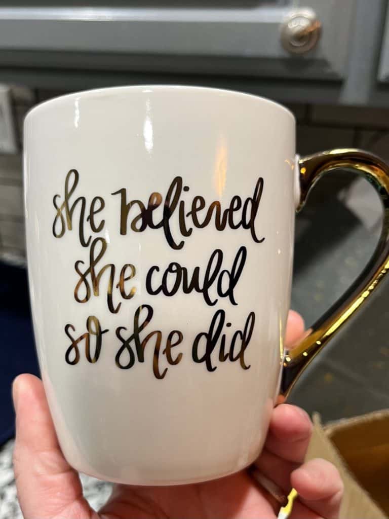 White mug with gold script reads "She believed she could so she did". Best gifts for homeschool moms.