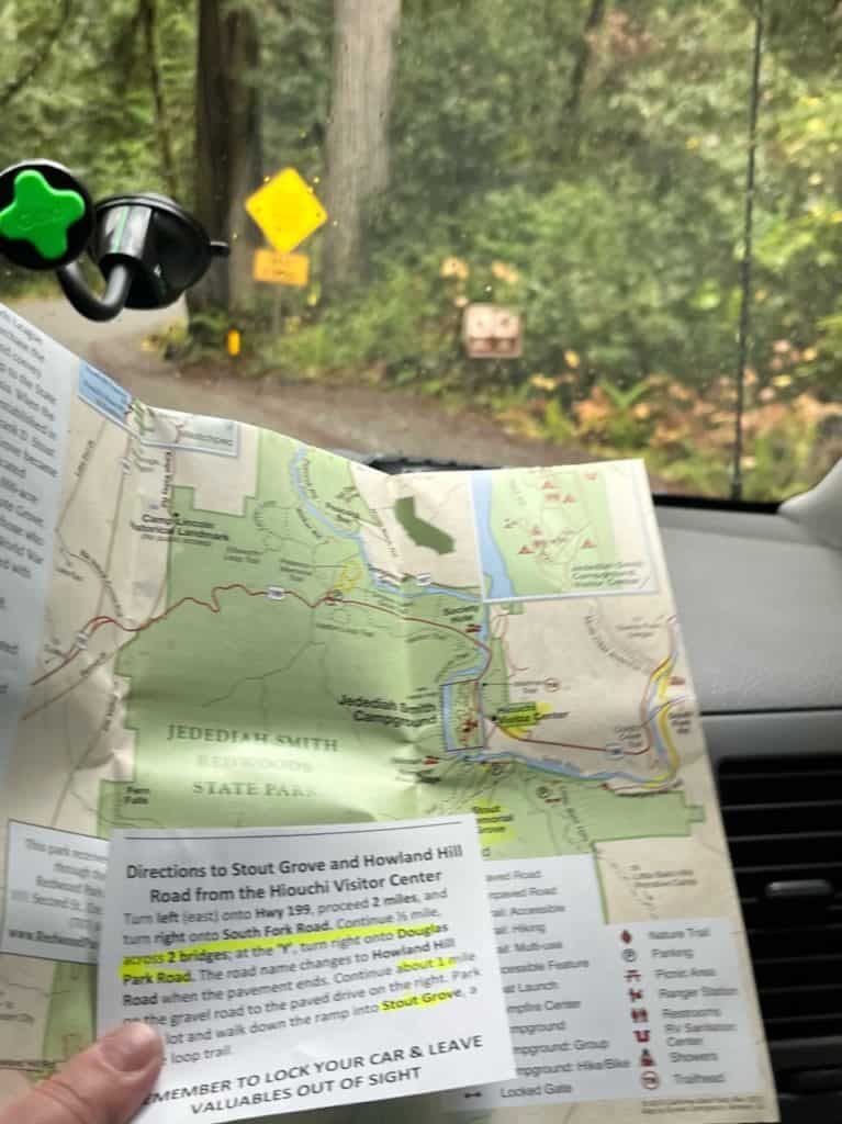 A passenger's hand holds up a highlighted map and directions for finding Grove of the Titans. Analog maps are a must if you want to know how to get to Redwood National Park.