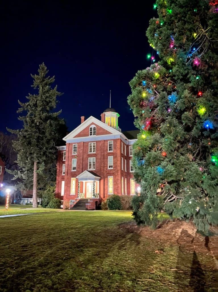 A historic university building stands grandly beside the Willamette University Star Trees. The Willamette University Start Trees are one of the 11 best places to see Christmas lights in Salem Oregon.