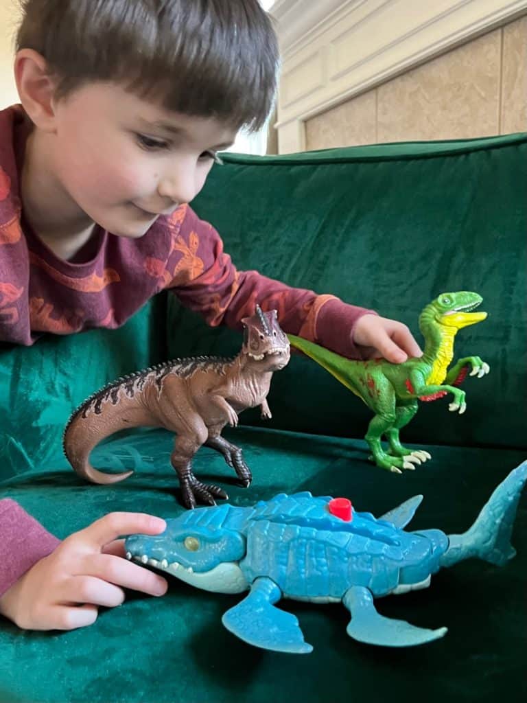 Boy playing with 3 different dinosaur figurines. Dinosaur gifts for a 5 year old.