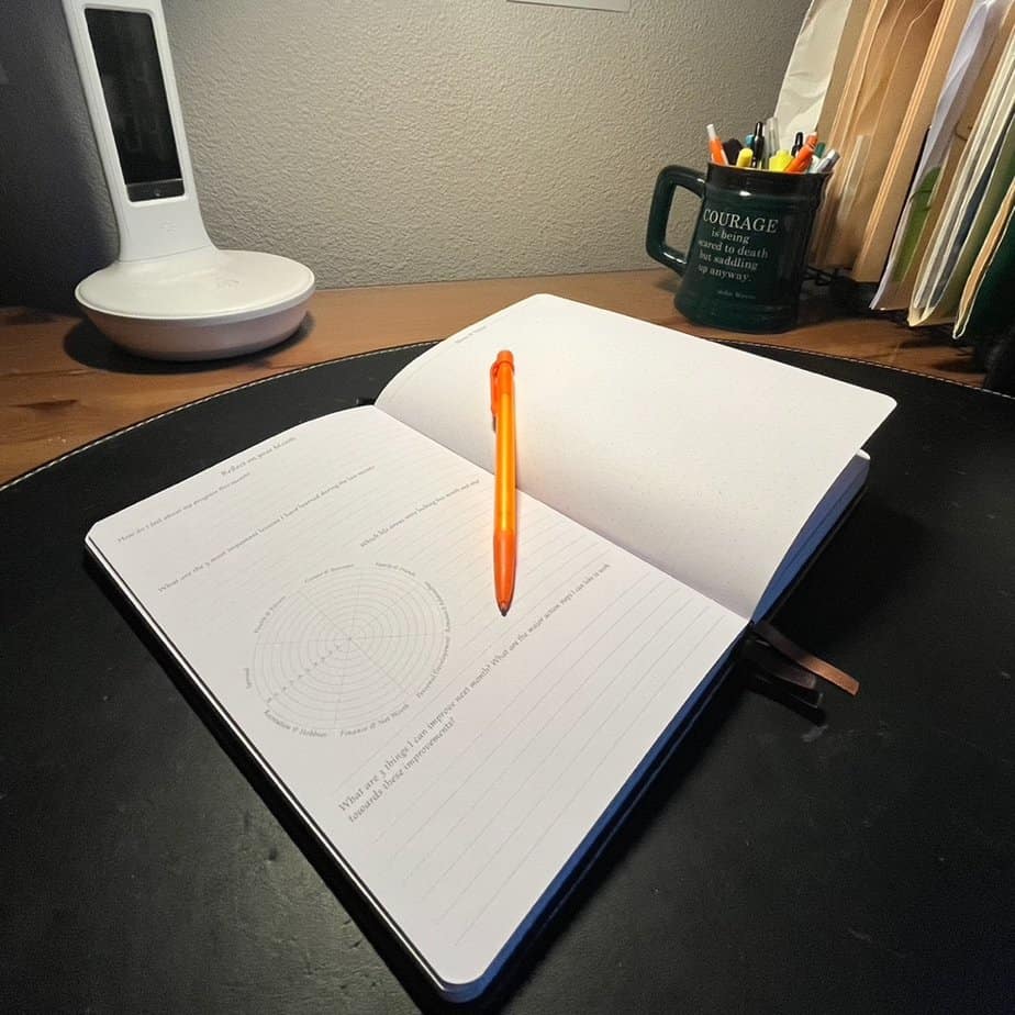Picture of an open Legend Planner sitting at a writing desk. The Legend Planner provide substantial opportunity for goal setting, planning, and reflection. It's well-designed, thorough features make it the best ADHD planner.