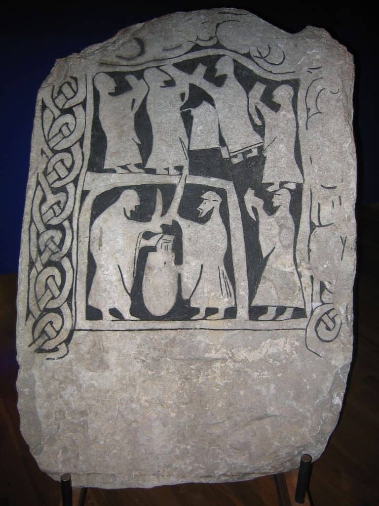 Vikings drink from drinking horns in an ancient sculpture of a viking drinking scene.