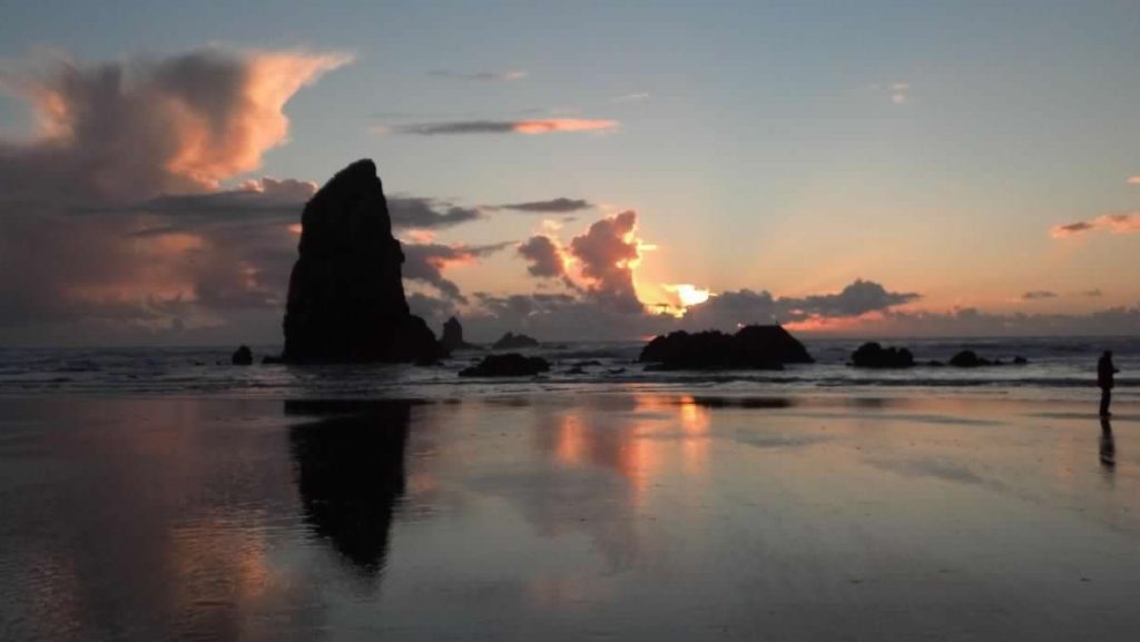 The sun sets behind the outline of sea stacks at Cannon Beach. Cannon Beach is one of the most beautiful places to explore the Oregon Coast with kids.