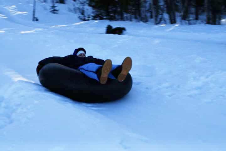 Woman in a snow tube going downhill. Winter activities for teens.