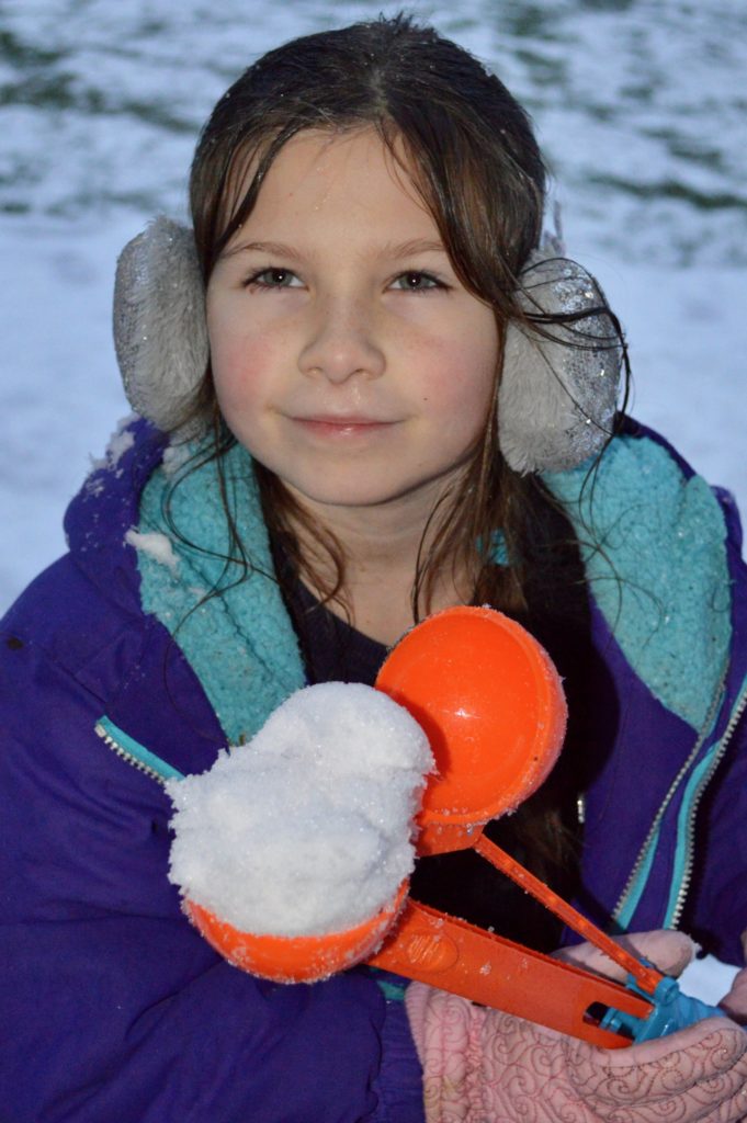 Girl with snowball in snowball maker.  Winter activities for teens.