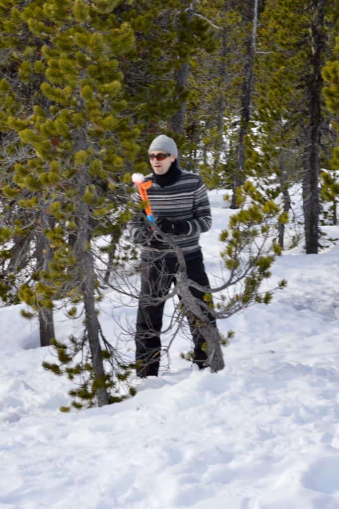 Dad hiding behind a tree with a snowball maker.  Winter activities for teens.
