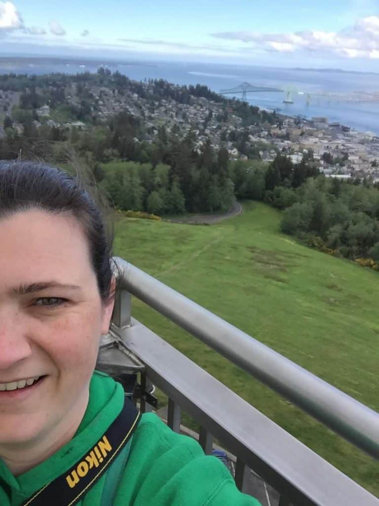 An amazing view of Astoria and the Columbia River expands beyond my wife in a phone selfie from the top of the Astoria Column. The Astoria Column is a great stop when traveling the Oregon Coast with kids.