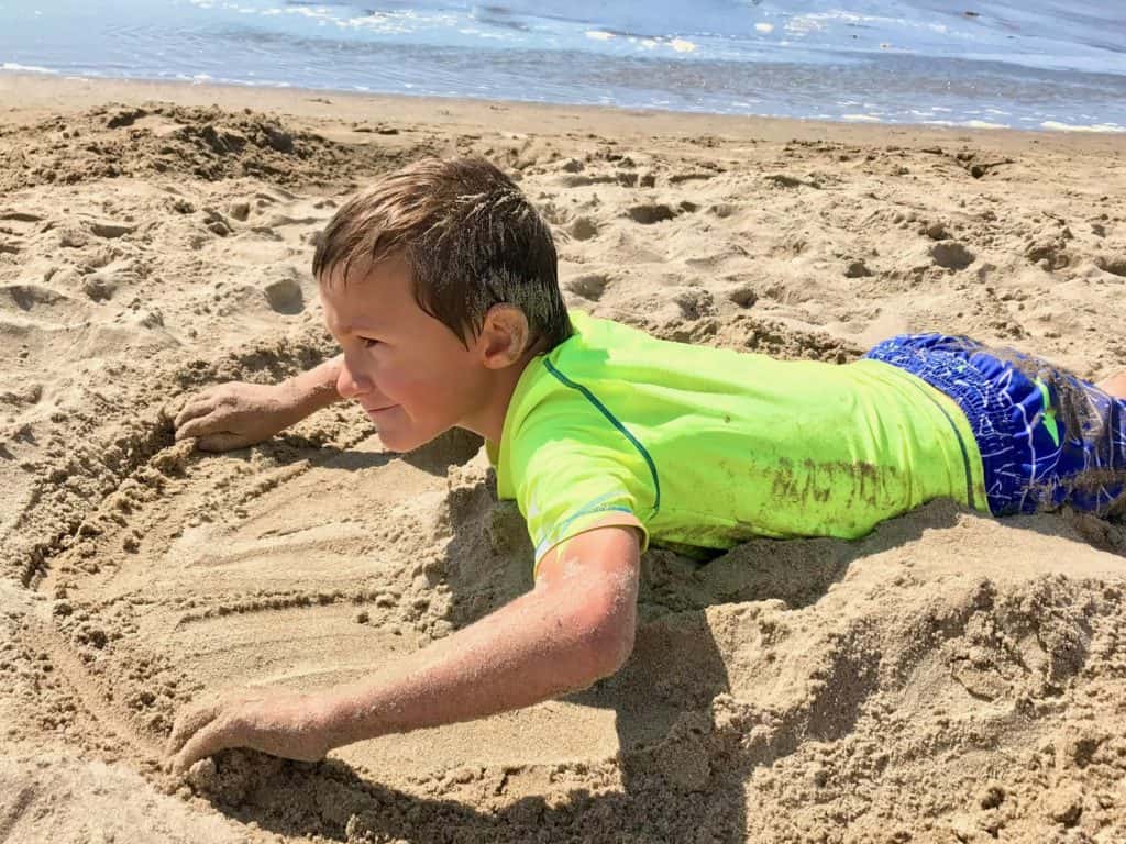 Boy playing in the sand. Beach packing list family.