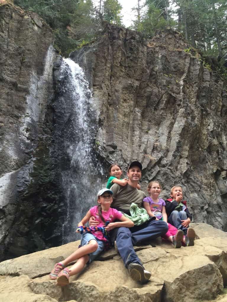 Four of my children and I sit on a rock beside Drift Falls. Drift Fall Trail is a great hike to consider when exploring the Oregon Coast with kids.