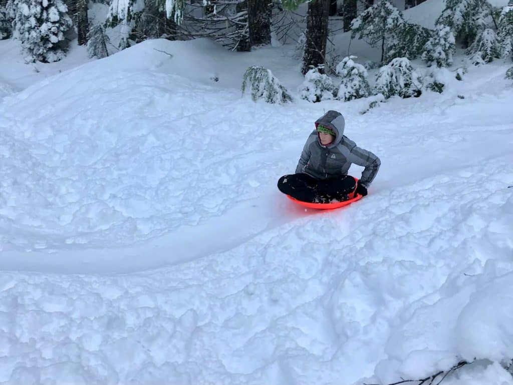 Girl sledding downhill. Winter Activities for Teens.