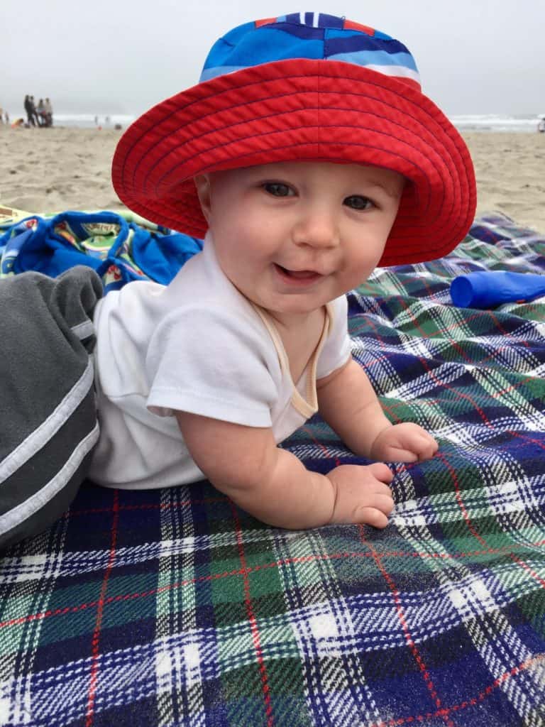 Baby on a plaid blanket at the beach. Beach packing list family.