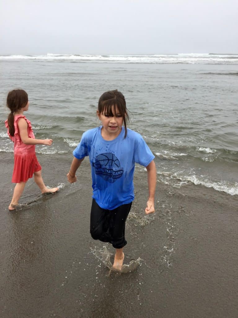 Girls in wet clothes playing at the beach. Beach packing list family.