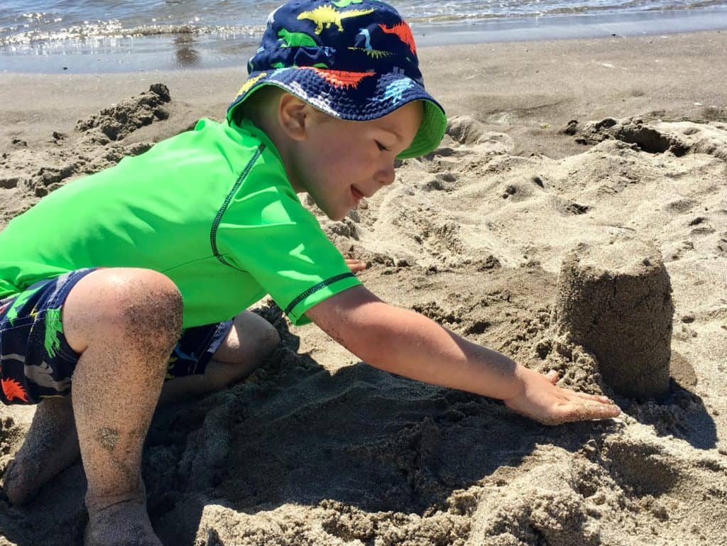 Boy building a sand castle. Beach packing list family.