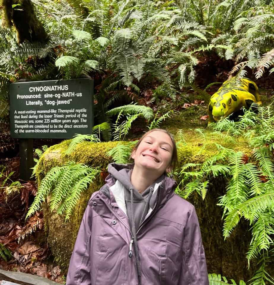 Our oldest daughter smiles beside a Cynognathus, a dog-sized dinosaur from the Triassic Period.