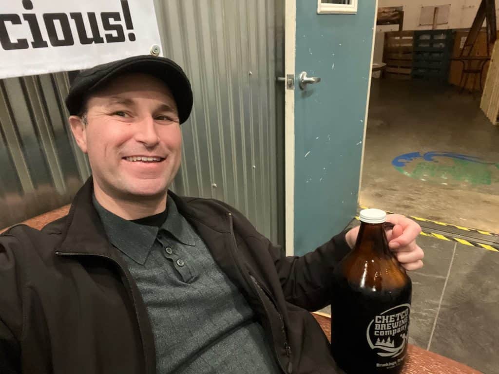 I smile with a growler of beer at Chetco Brewing. 
