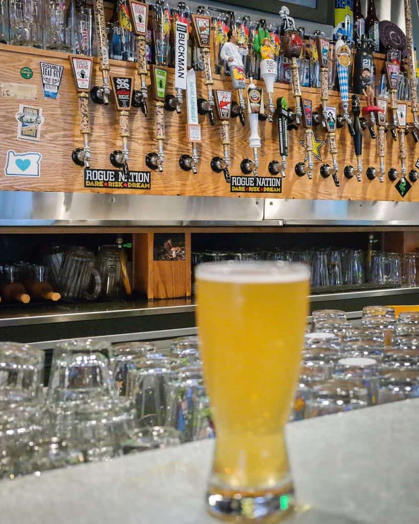 A tall glass of beer stands on a bartop at Rogue taphouse. Rogue is the best known of the breweries Oregon Coast.