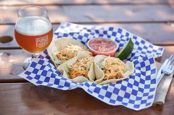 A glass of beer stands next to fresh made fish tacos at Public Coast brewing. Public Coast brewing is one of best breweries Oregon Coast.